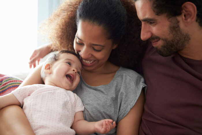 Man, woman and small child sitting close together and smiling.